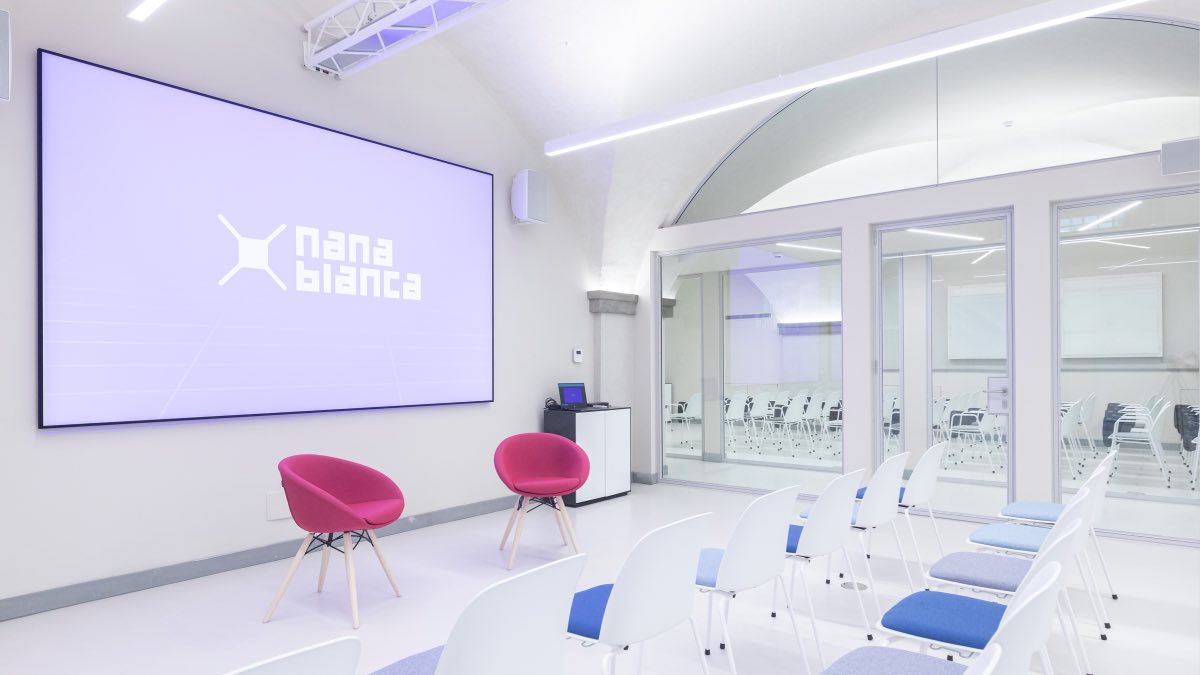 Sala eventi di Nana Bianca con schermo e brand sul muro